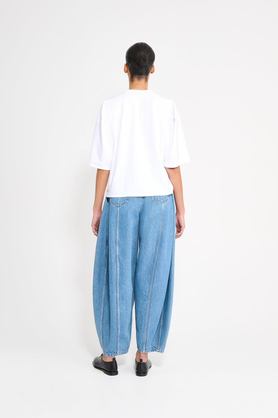 Person wearing a white shirt and blue jeans on a white background