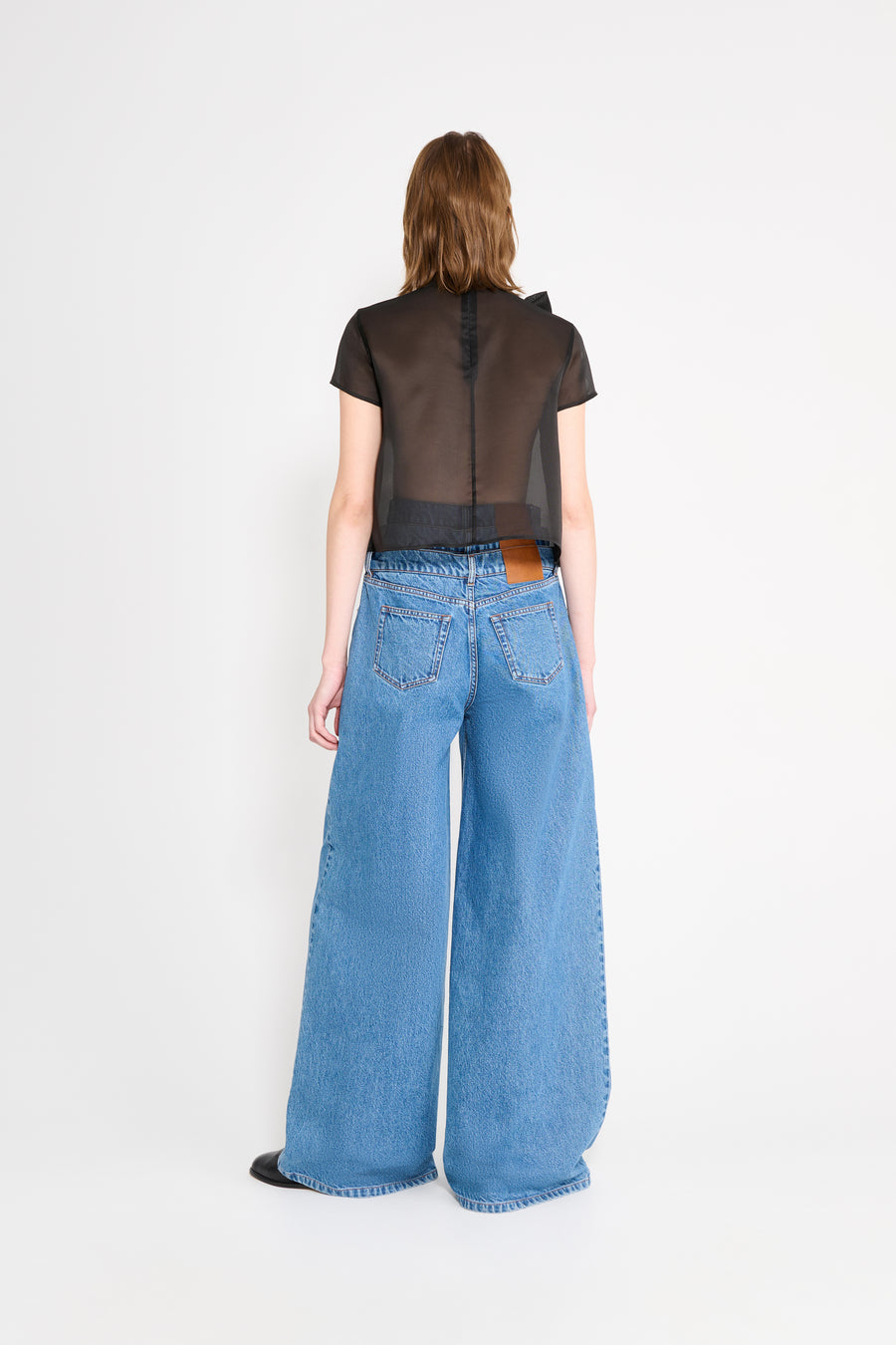 Person wearing a black top and blue jeans on a white background