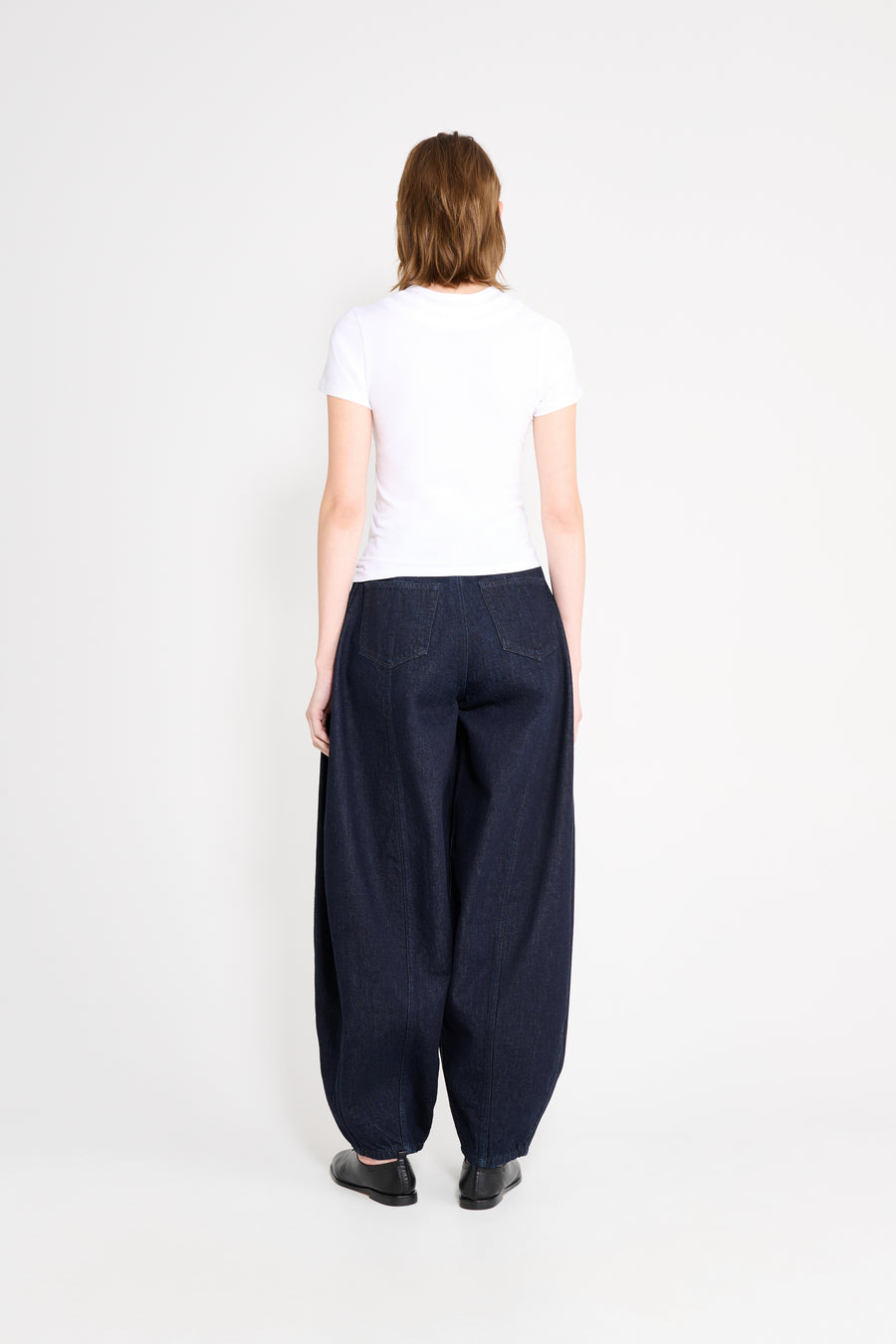 Person wearing a white t-shirt and dark blue wide-leg pants on a white background