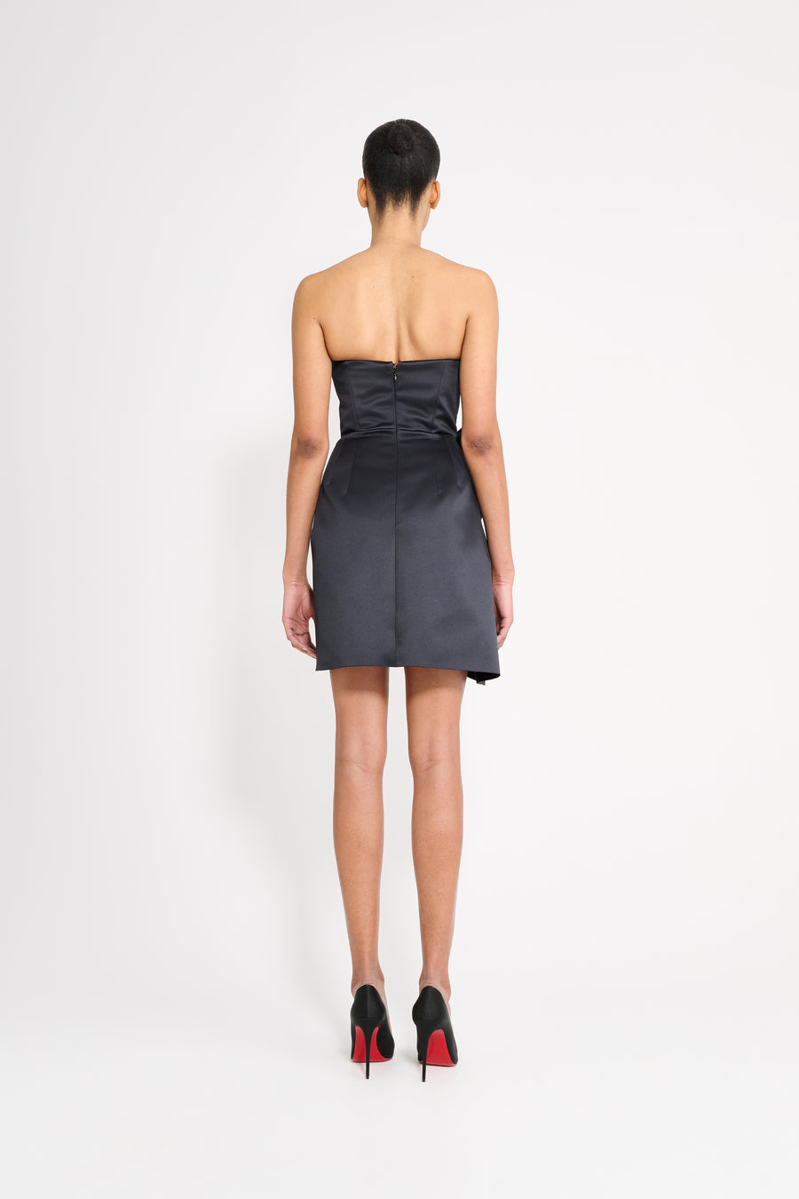 Model wearing a black mini dress on a white background.