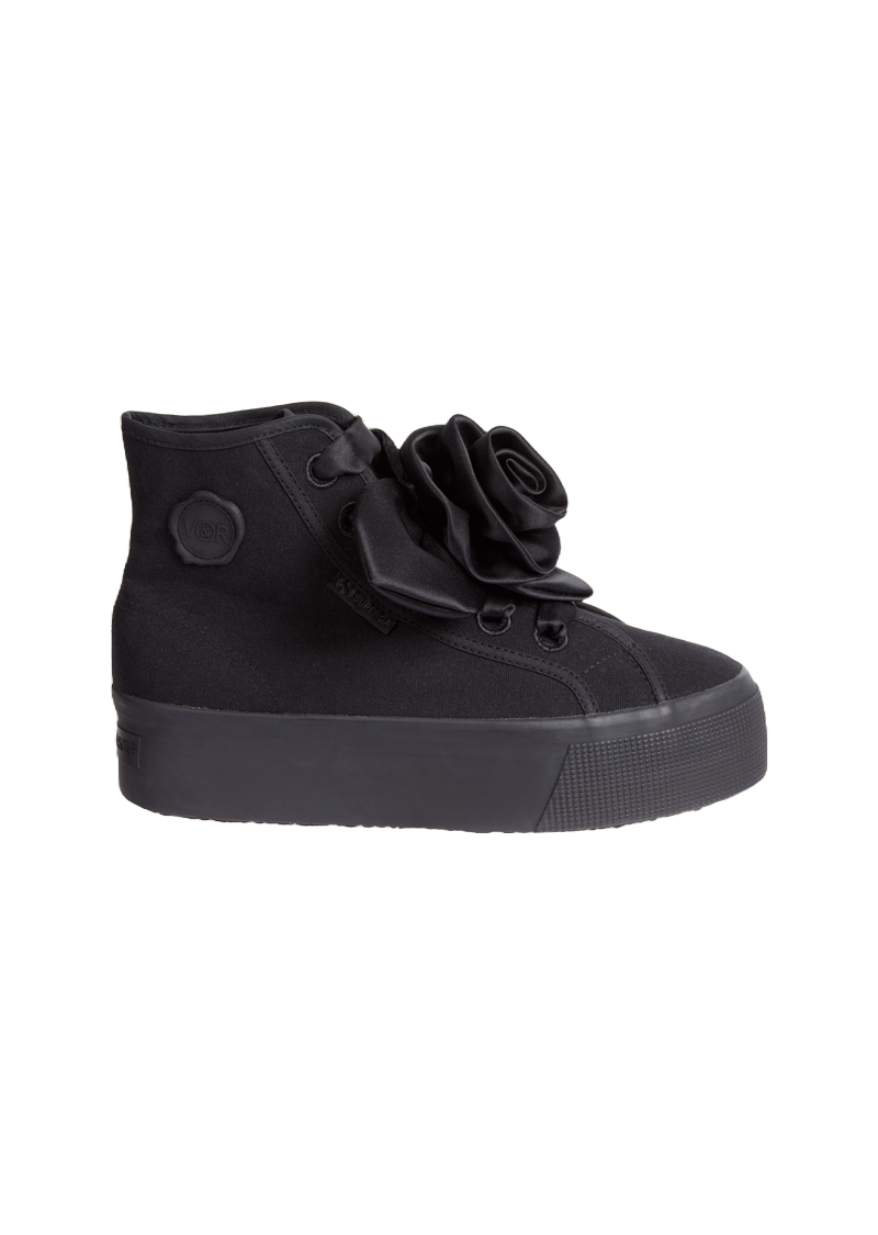 The sneaker features a black canvas body with an elegant satin floral rosette adorned on the side, complemented by rubber soles.