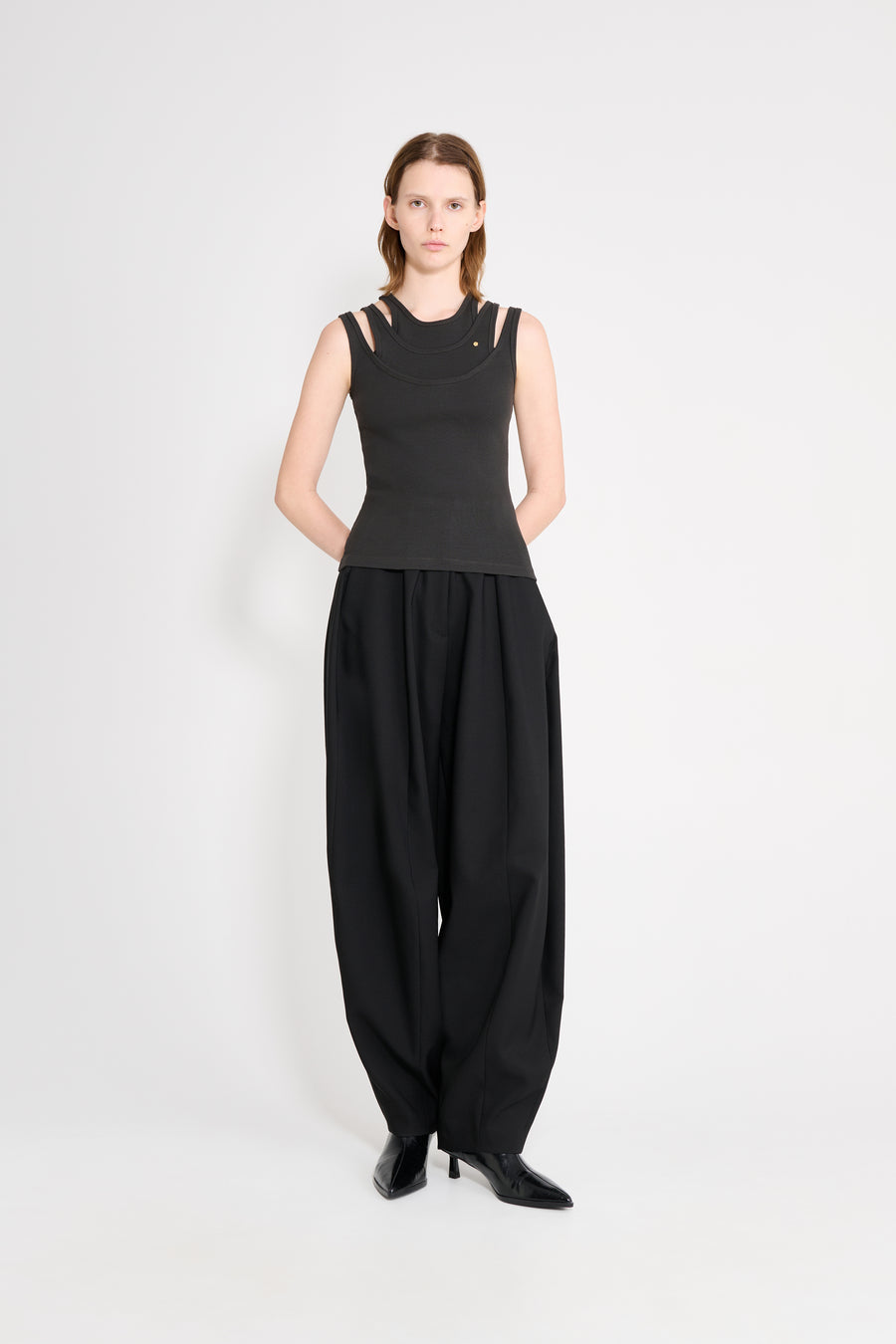 Woman wearing a black sleeveless top and wide-leg pants on a white background