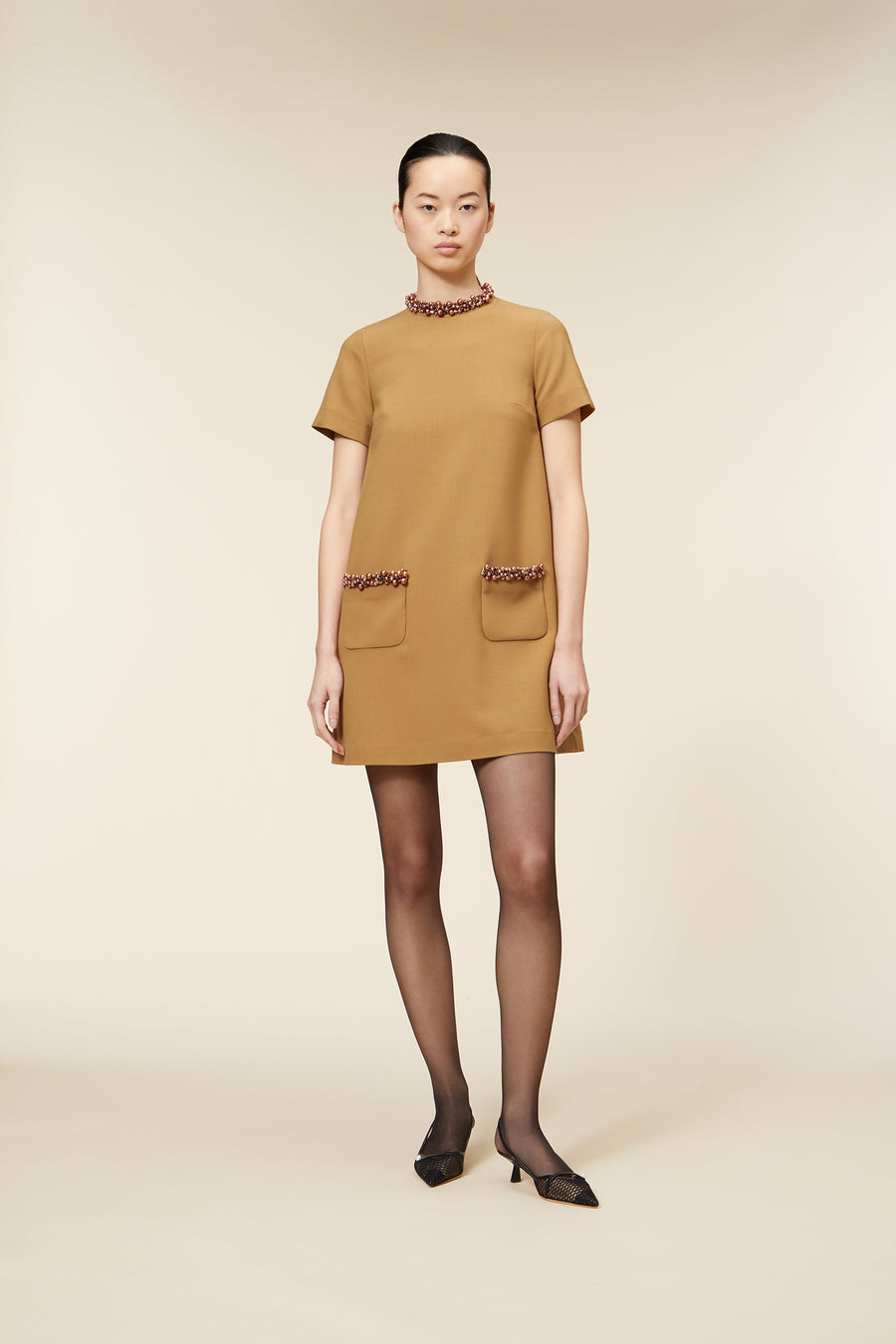 Elegant mustard-colored dress with beaded trim on pockets and collar, featuring short sleeves and a straight silhouette.