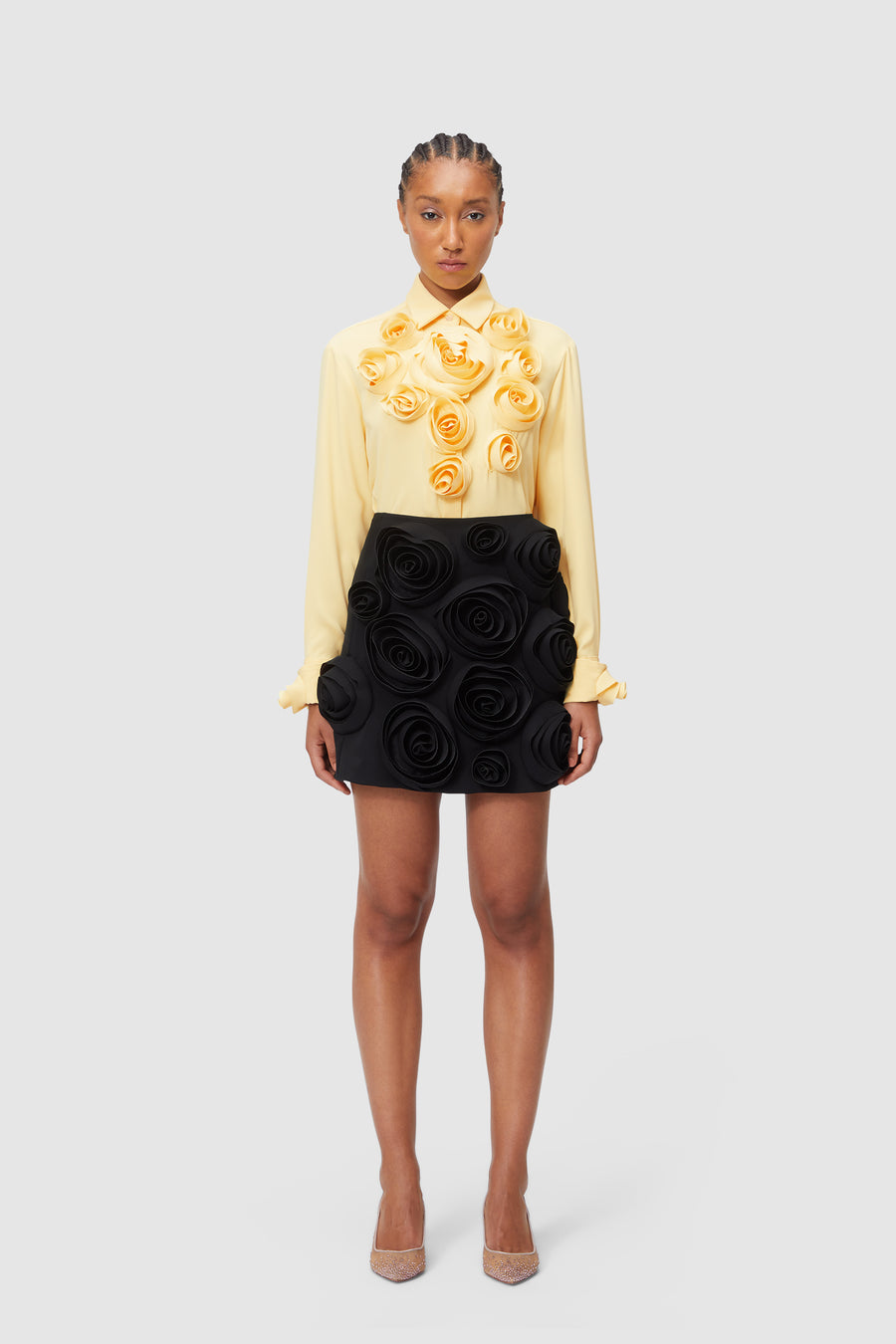 Yellow blouse with cascading floral appliques paired with black skirt adorned in layered rose designs.