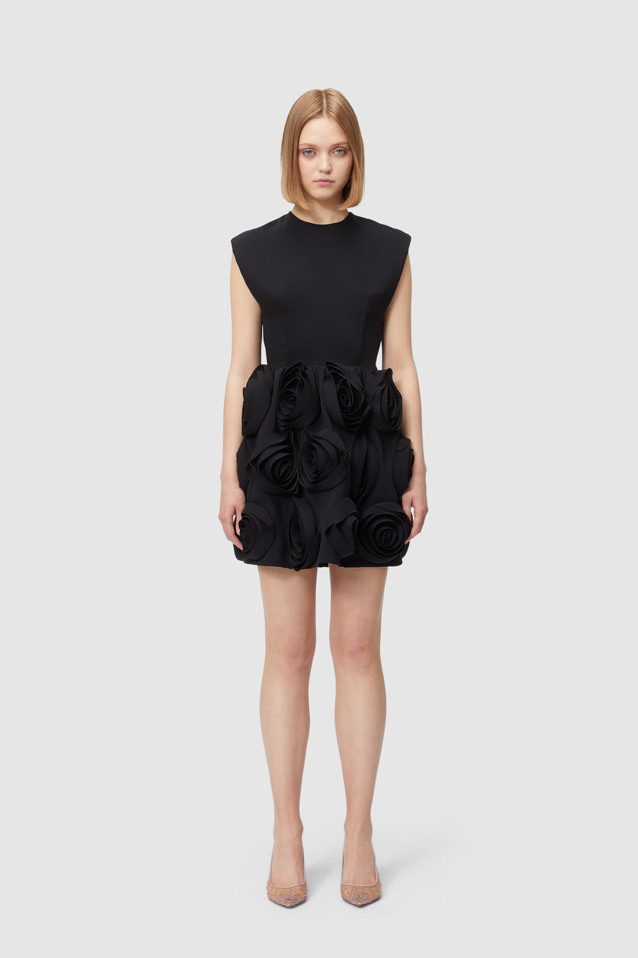 Elegant black dress adorned with large sculpted rose details on the skirt, featuring a sleek, minimalist bodice.