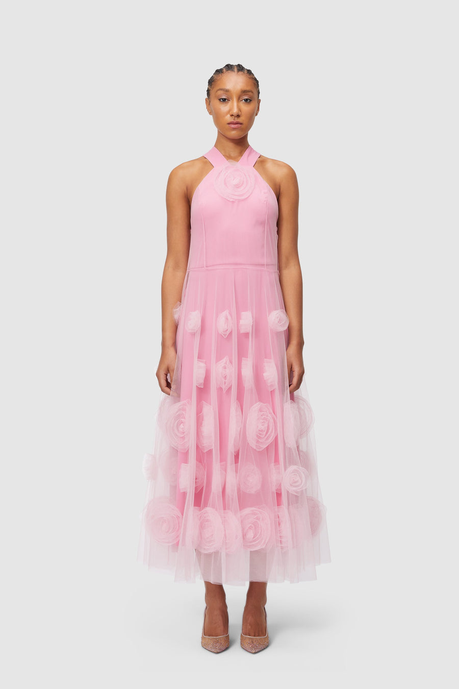 Elegant evening dress in pastel pink tulle with intricate floral appliqués, featuring a halter neckline and flowing silhouette.