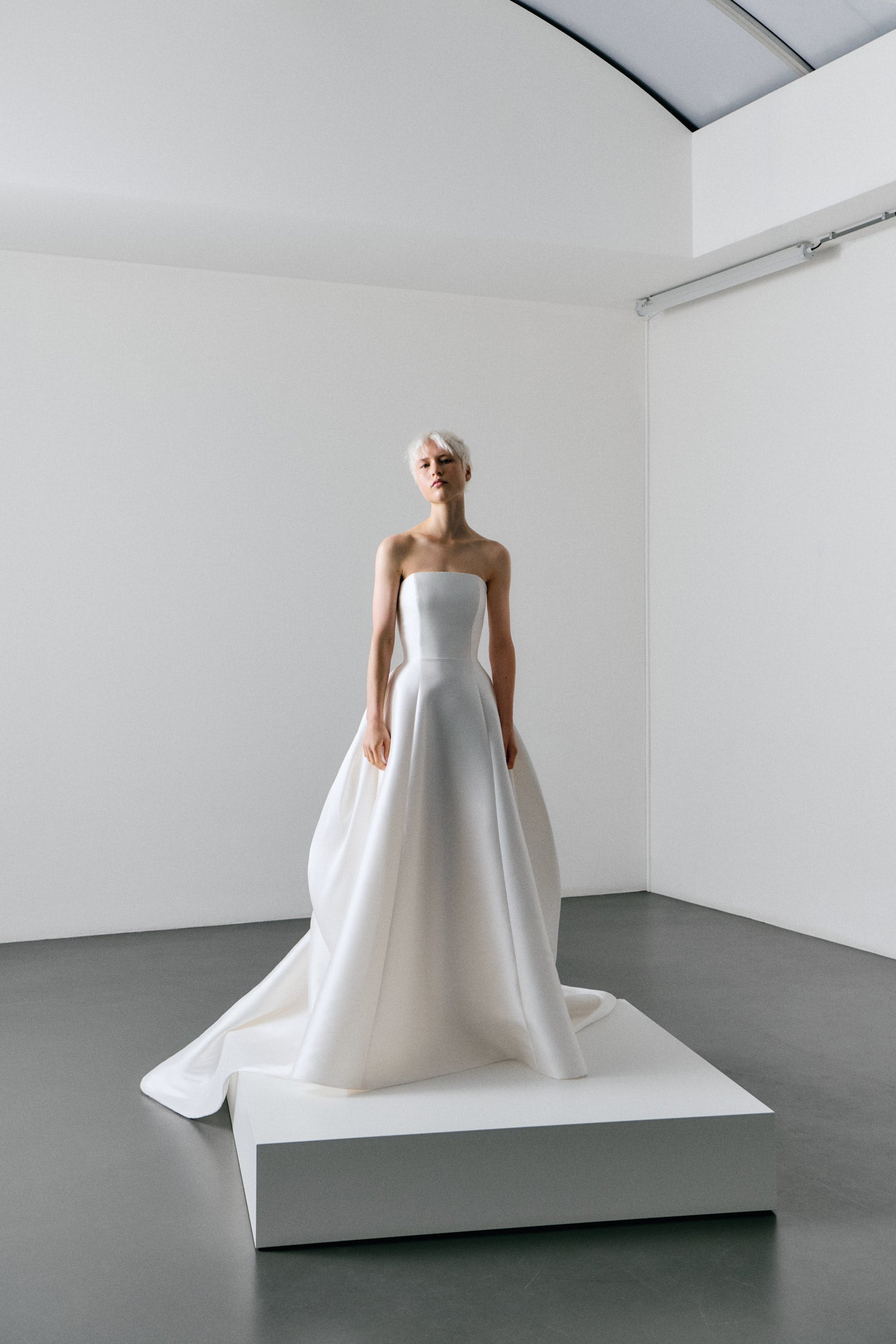 White wedding dress on a mannequin in a minimalistic room.