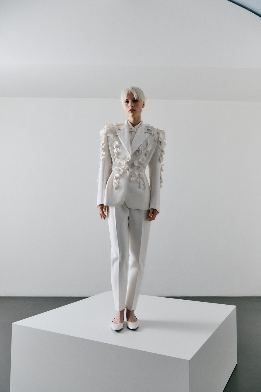 White floral embroidered suit on a mannequin against a plain background