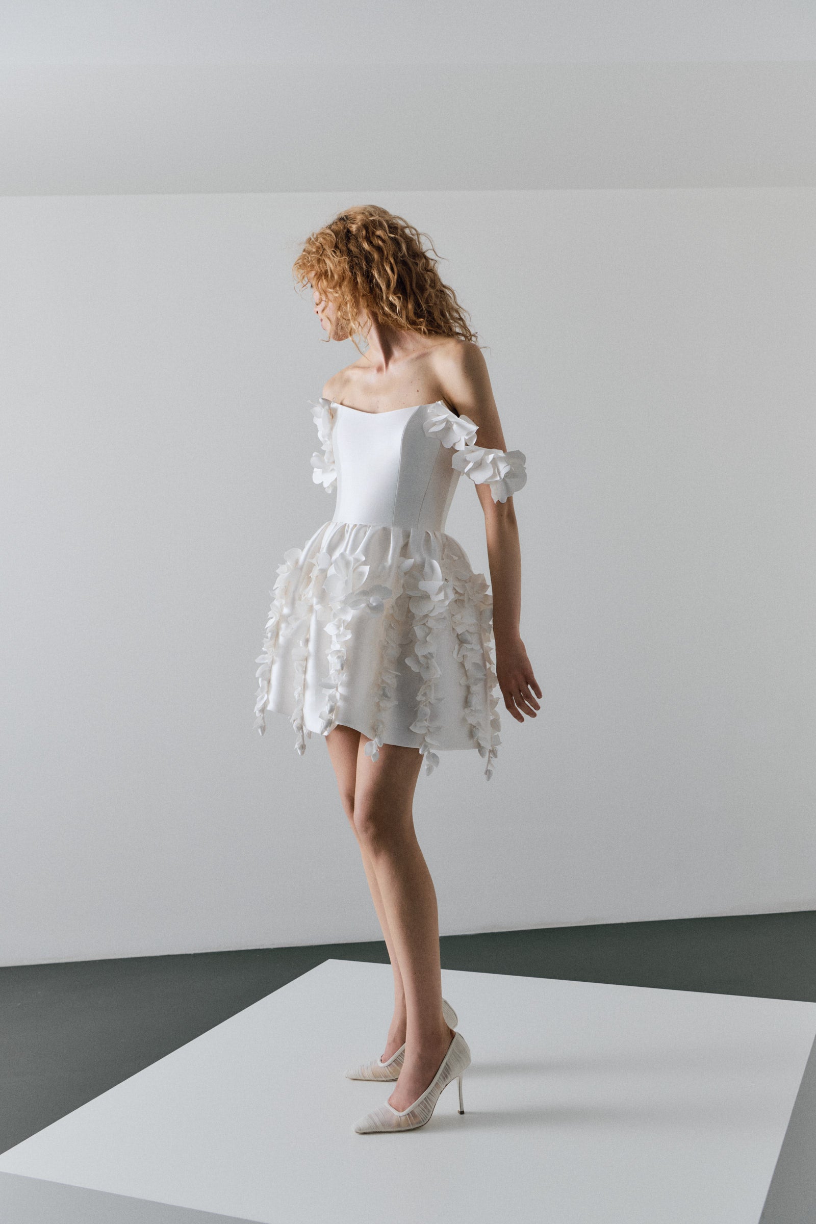 Woman wearing a white floral dress on a plain background
