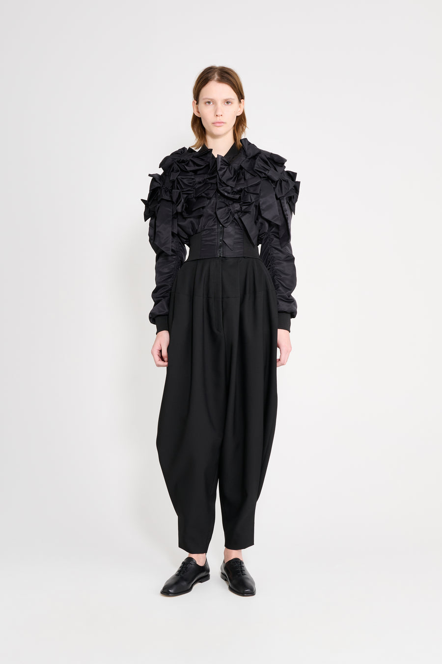 Person wearing a black outfit with ruffled top and wide-leg pants on a white background