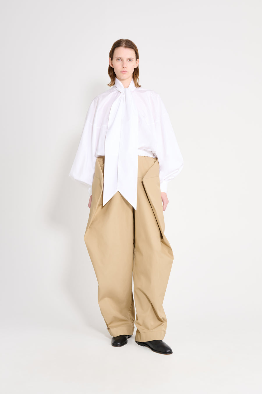 Person wearing a white shirt and beige pants on a white background