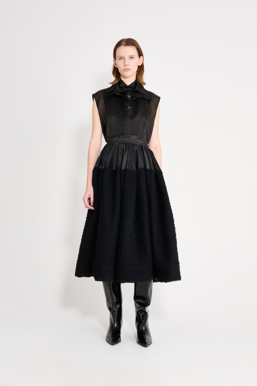 Woman wearing a black sleeveless dress with a ruffled collar on a white background