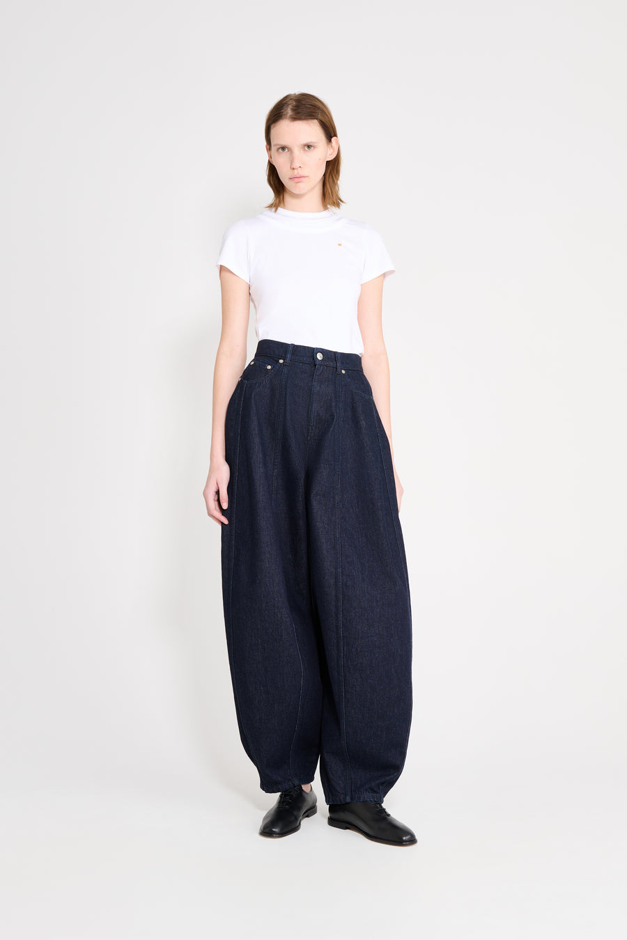 Woman wearing a white t-shirt and dark blue wide-leg pants on a white background
