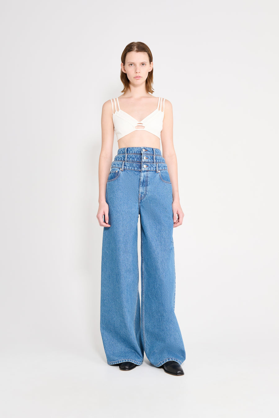 Woman wearing a white top and blue jeans on a white background