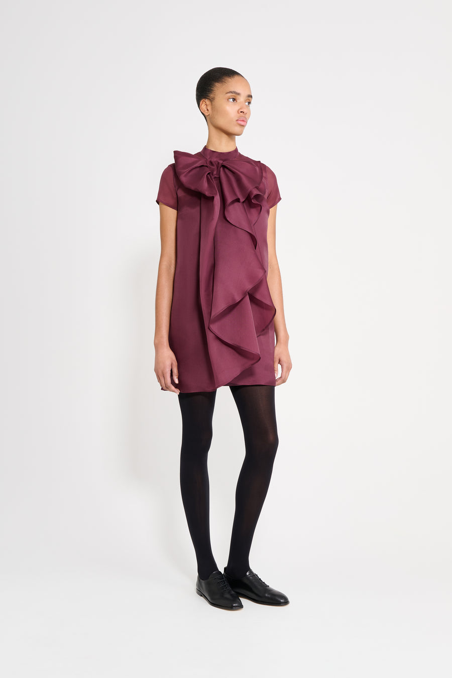 Woman wearing a burgundy dress with ruffled details on a white background