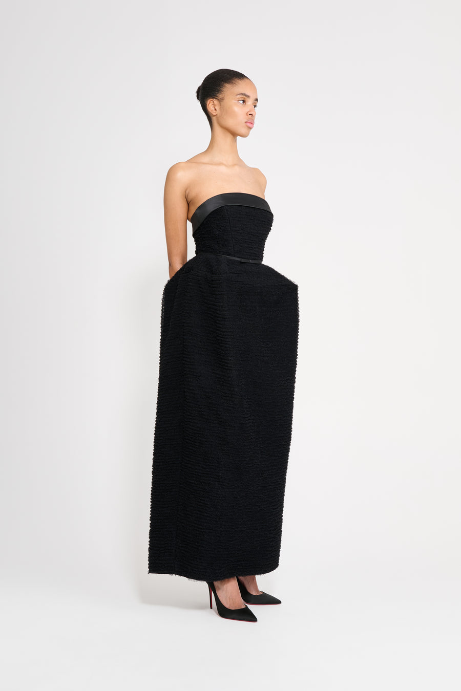 Woman wearing a black strapless gown on a white background