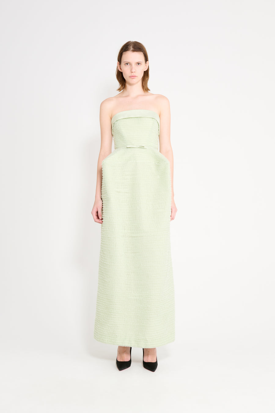 Woman wearing a light green strapless gown on a white background