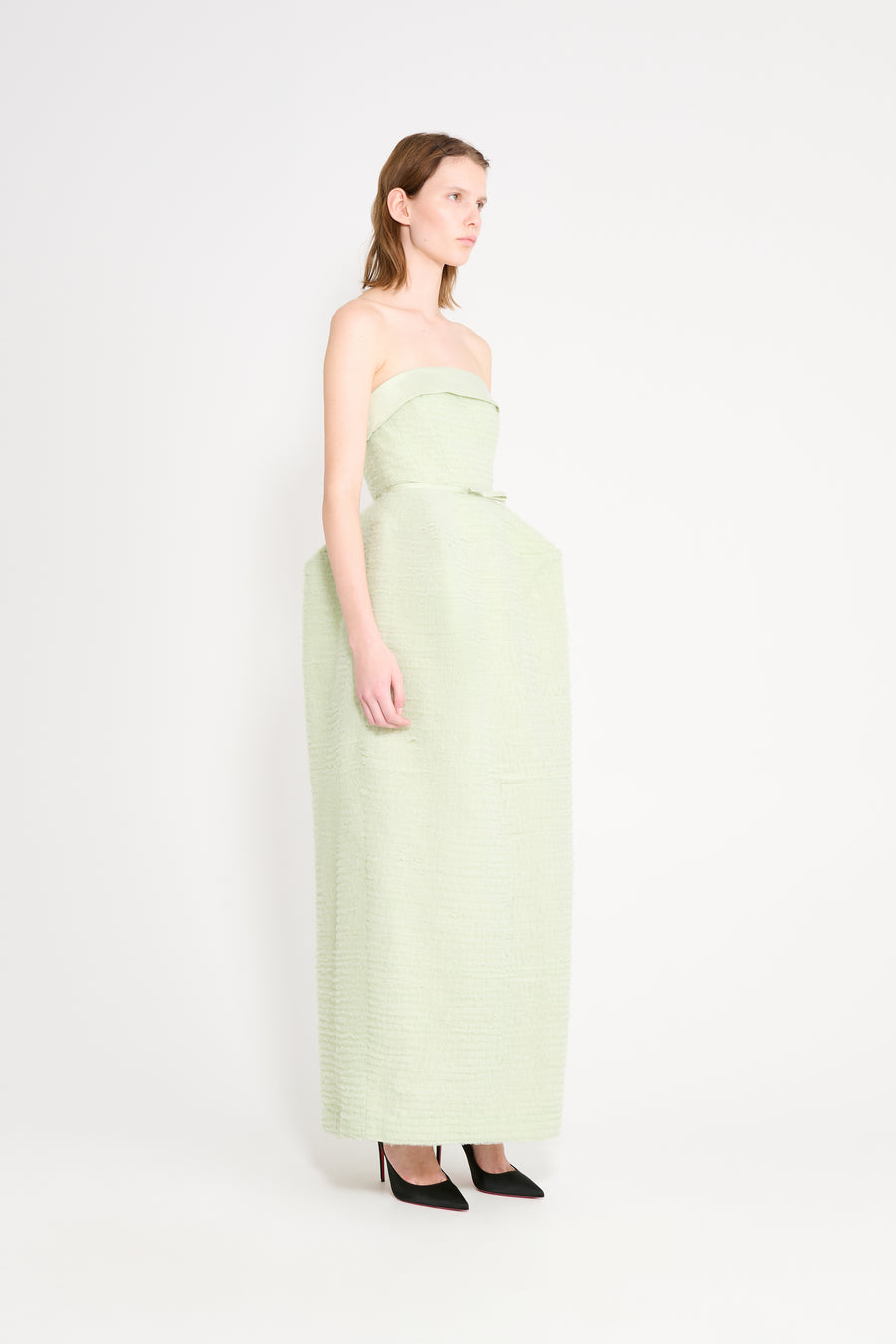 Woman wearing a light green strapless dress on a white background