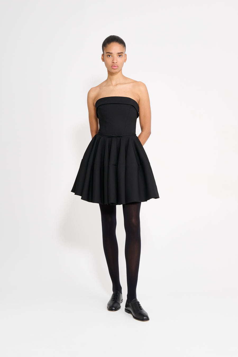 Woman wearing a black strapless dress on a white background