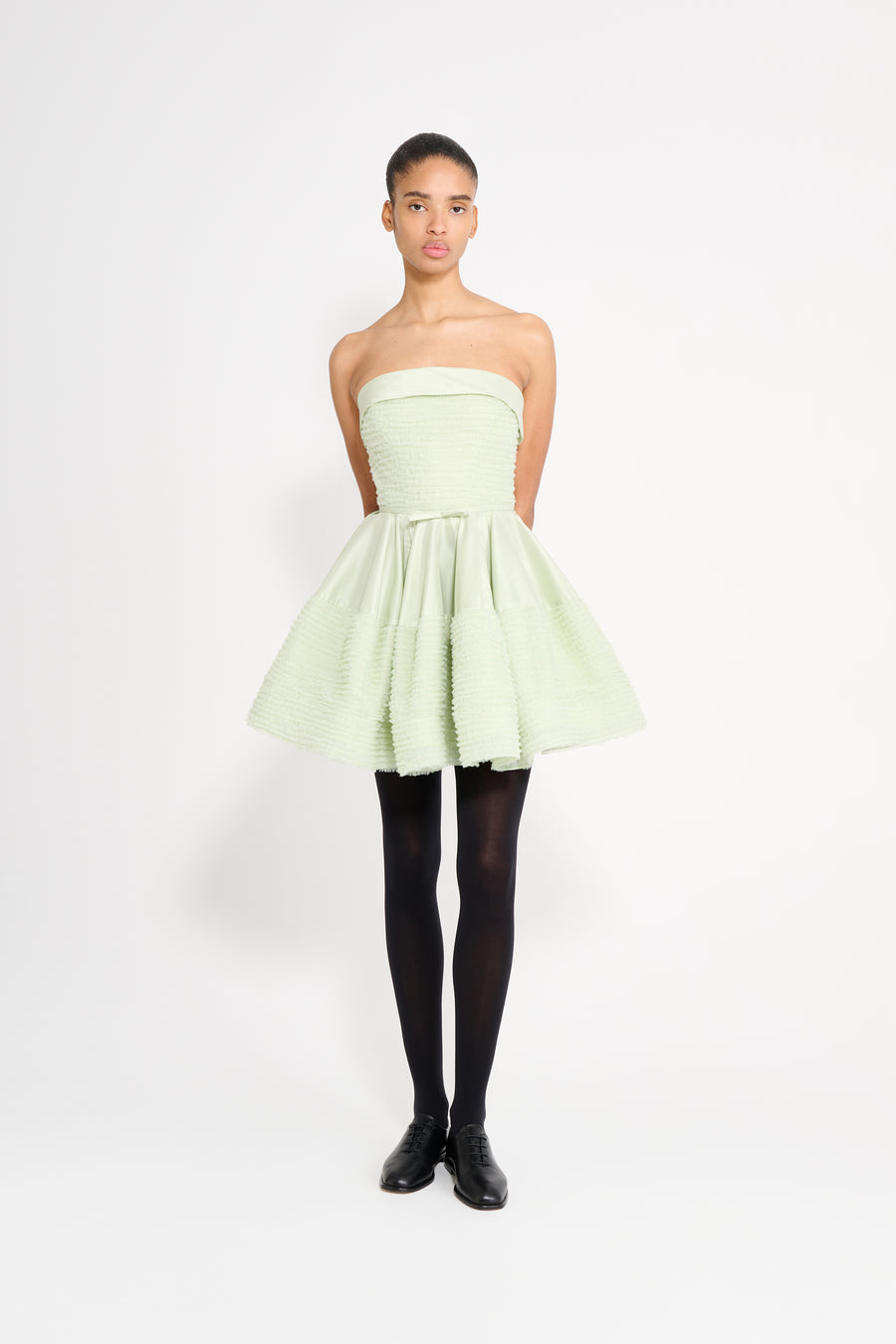 Woman wearing a light green strapless dress on a white background