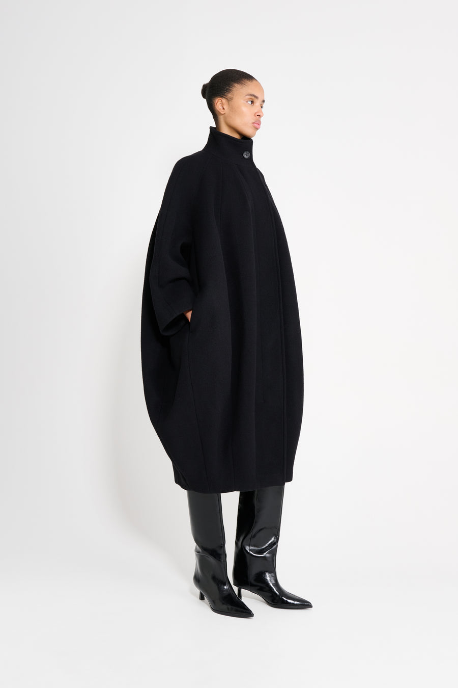 Model wearing a black coat on a white background.