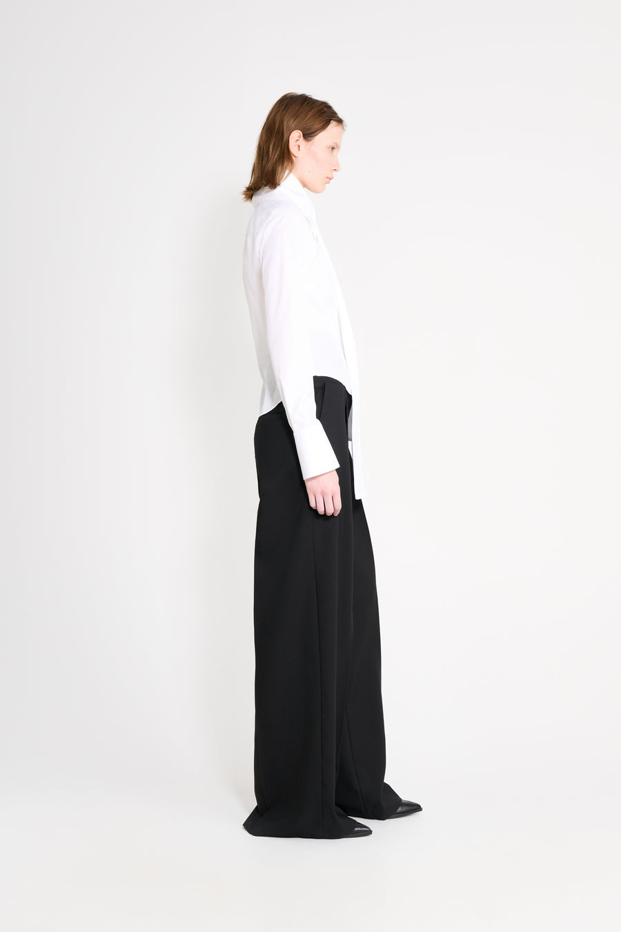 Person wearing a white shirt and black pants on a white background