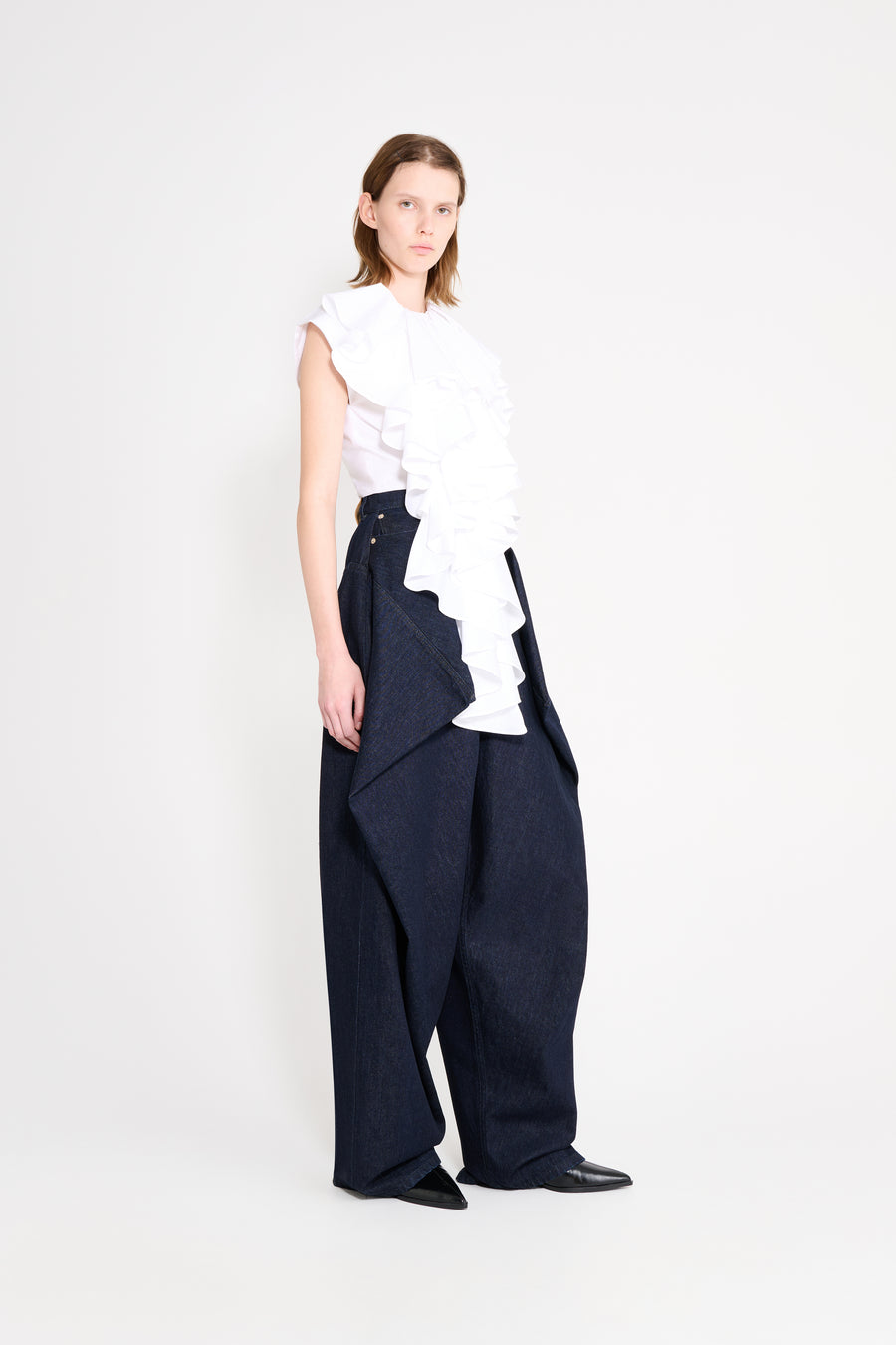 Person wearing a white top and navy pants on a white background