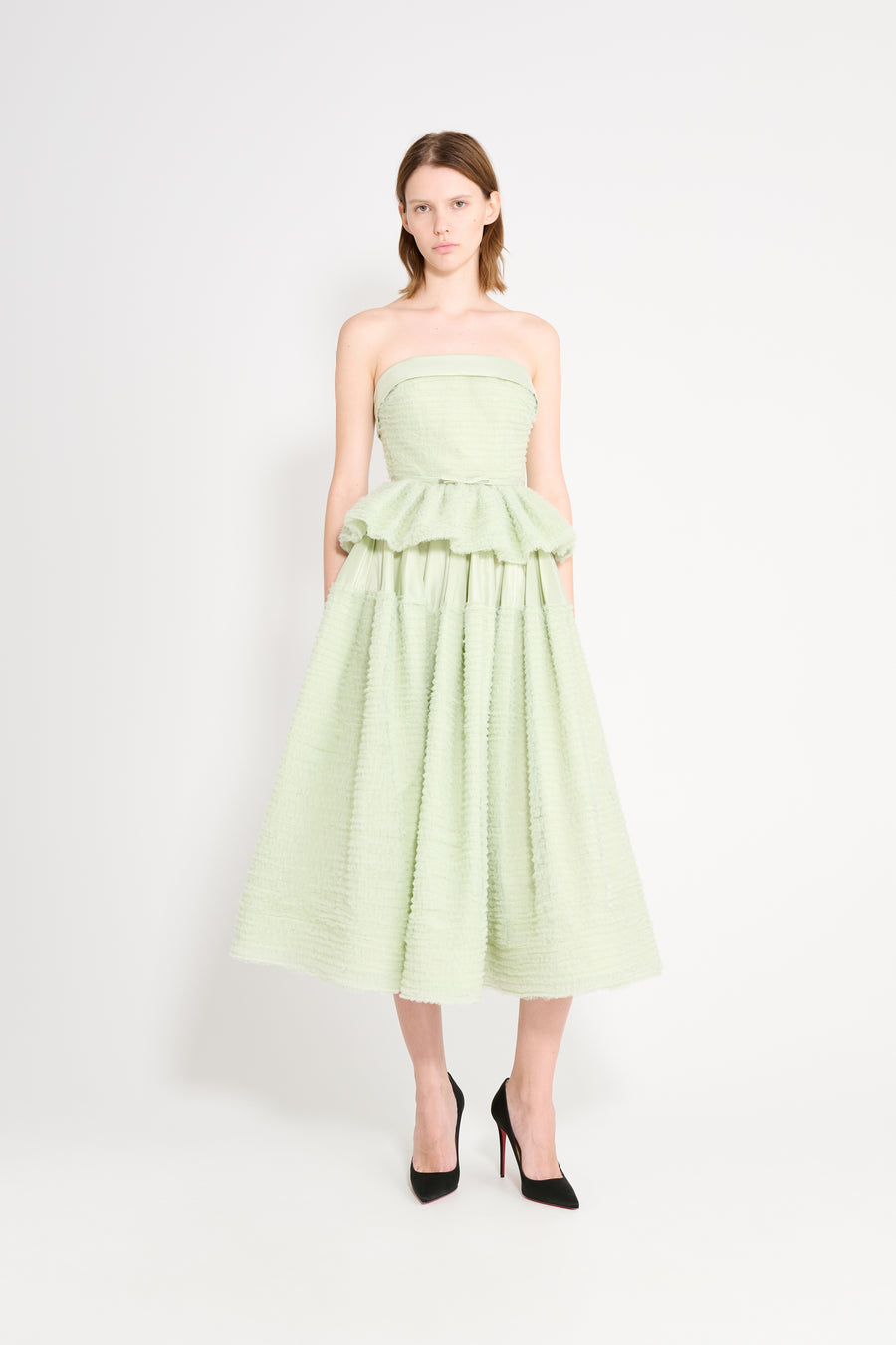 Woman wearing a light green strapless dress on a white background