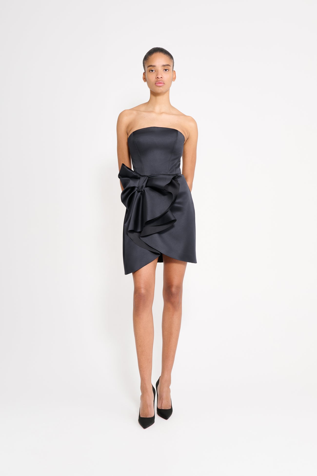 Model wearing a black mini dress on a white background