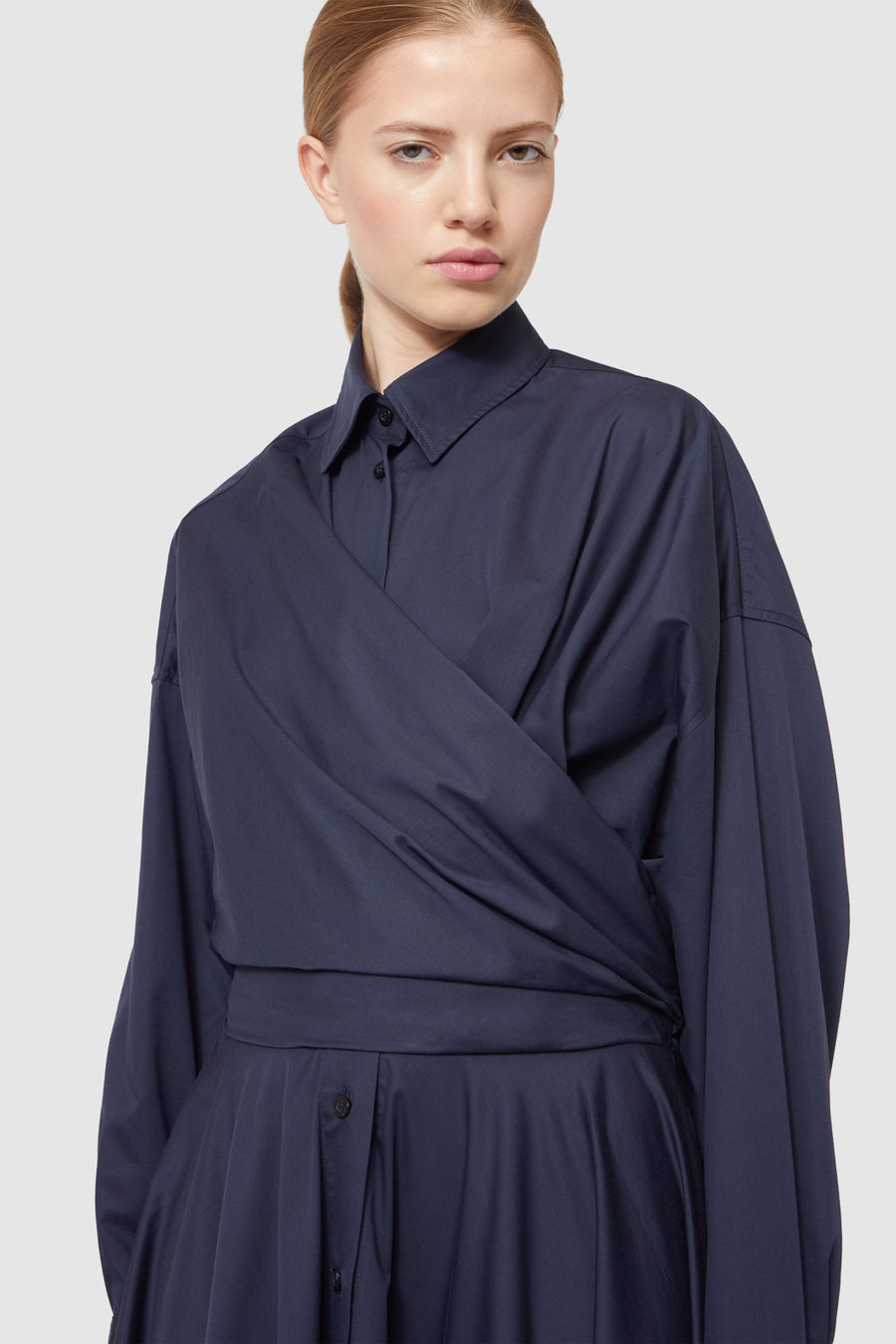 Navy blue wrap dress with a collared neckline and long sleeves, featuring a contemporary silhouette and button detailing.