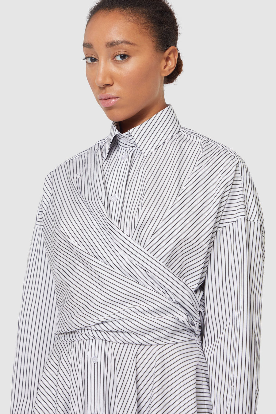 Striped white cotton shirt with asymmetrical wrap design, featuring a classic collar and button-down detailing.