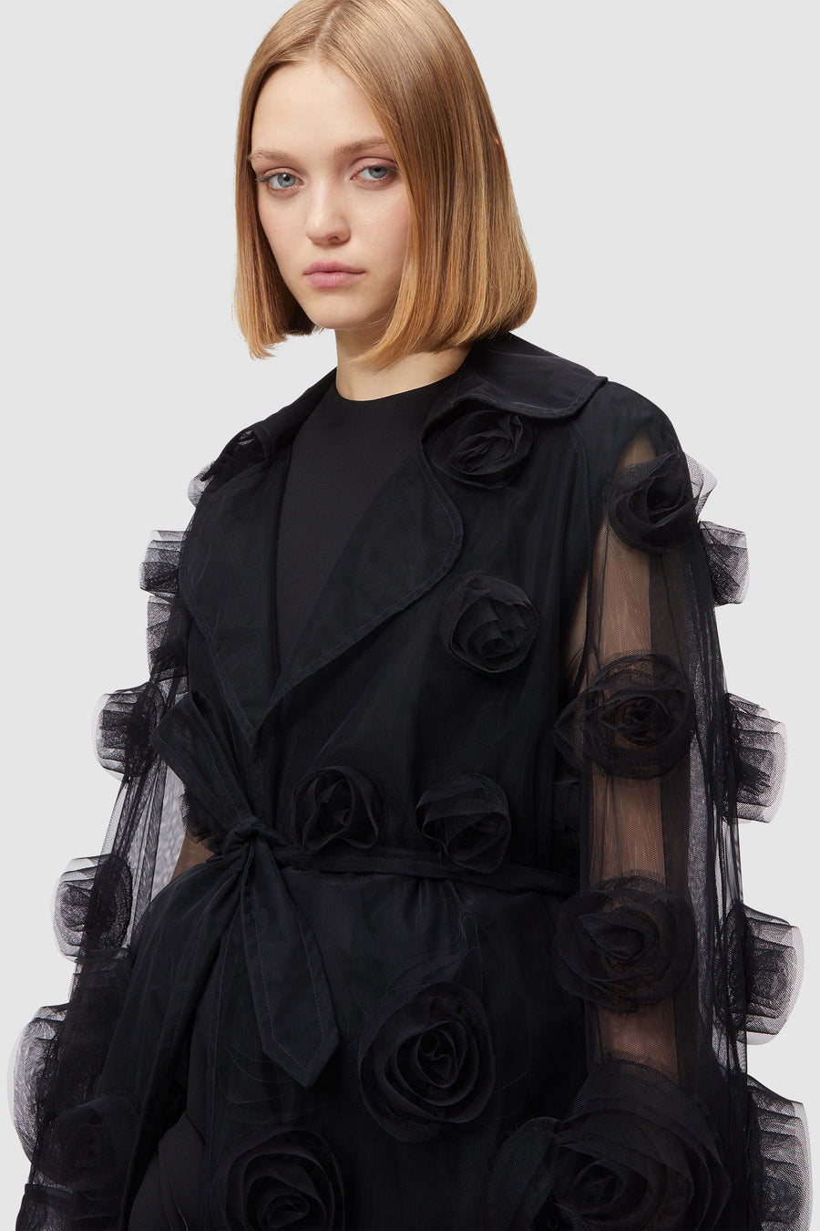 Luxurious black tulle coat adorned with 3D floral appliqués, elegantly layered over a sleek black dress.