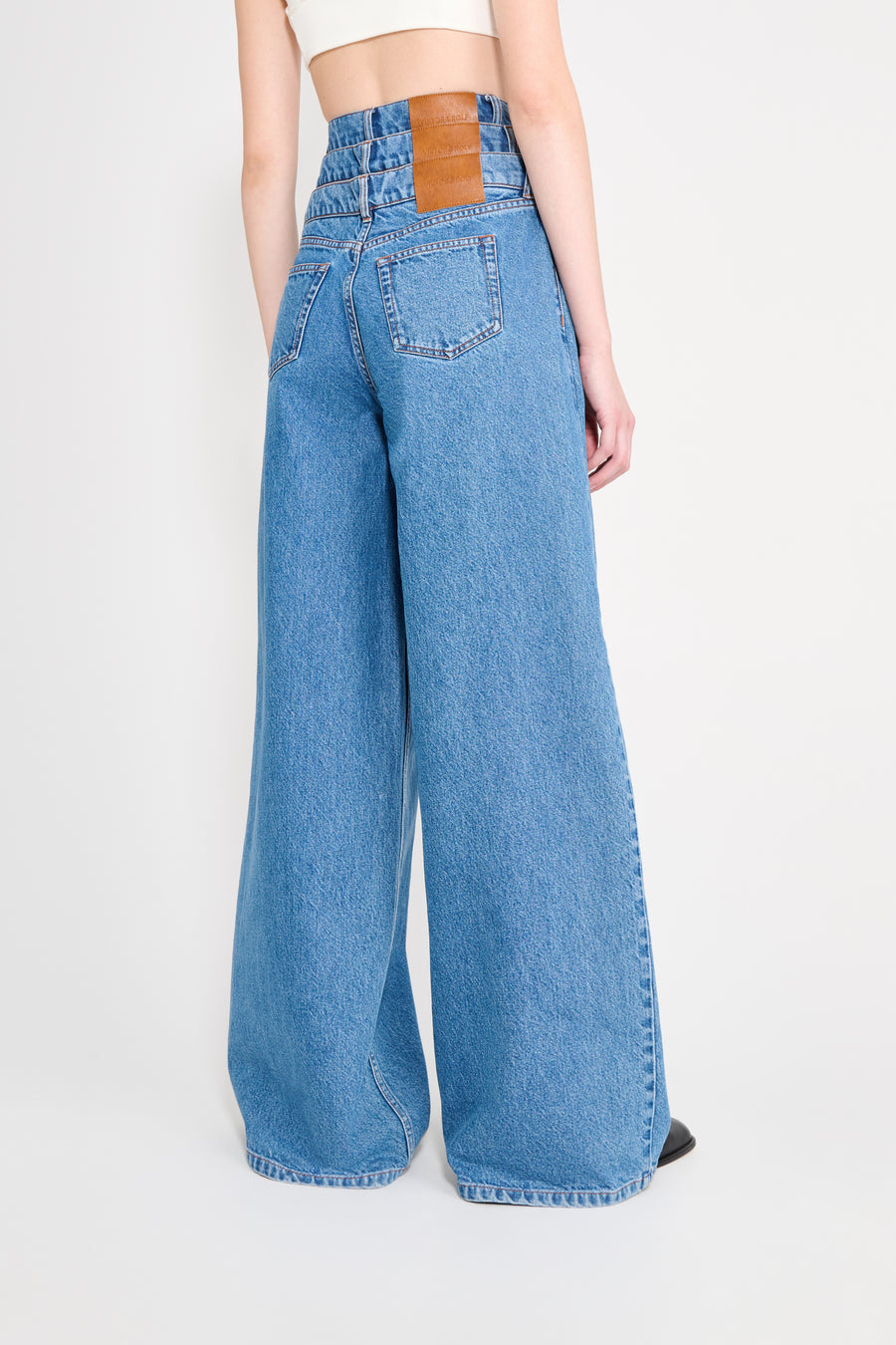 Person wearing blue wide-leg jeans on a light gray background