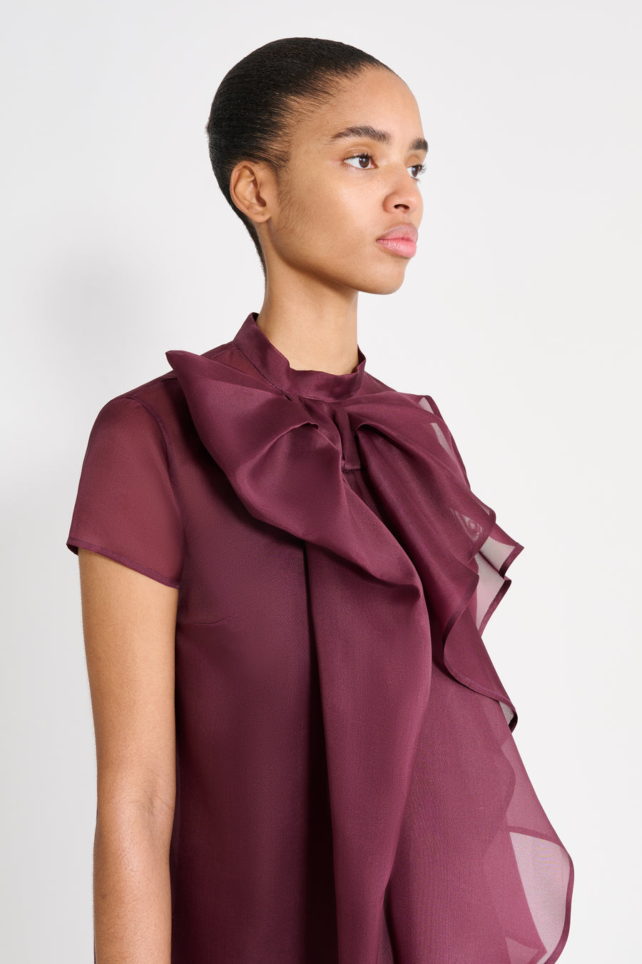 Woman wearing a burgundy blouse with a large bow on a white background