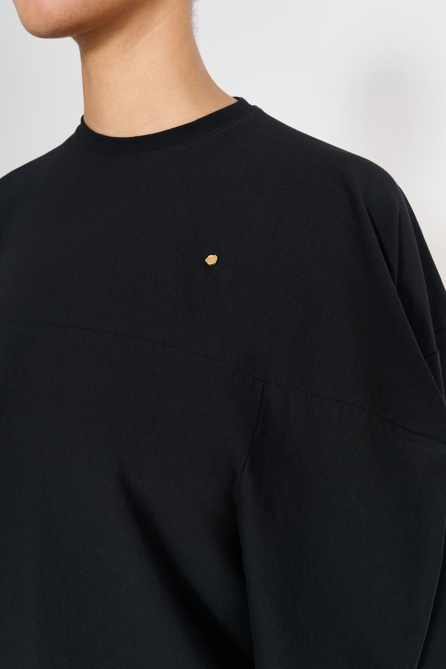 Black shirt with a gold logo on a plain background