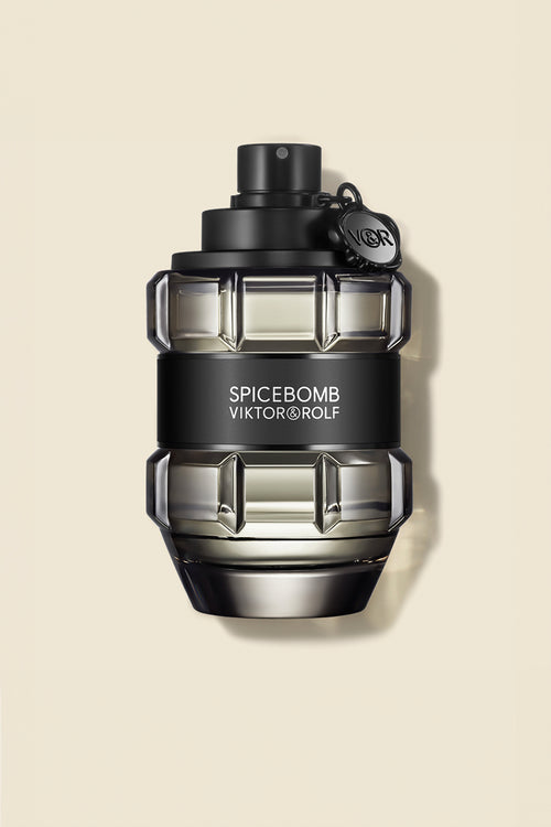 Elegant grenade-shaped bottle of Viktor & Rolf Spicebomb fragrance with a sleek black cap and label on a beige backdrop.