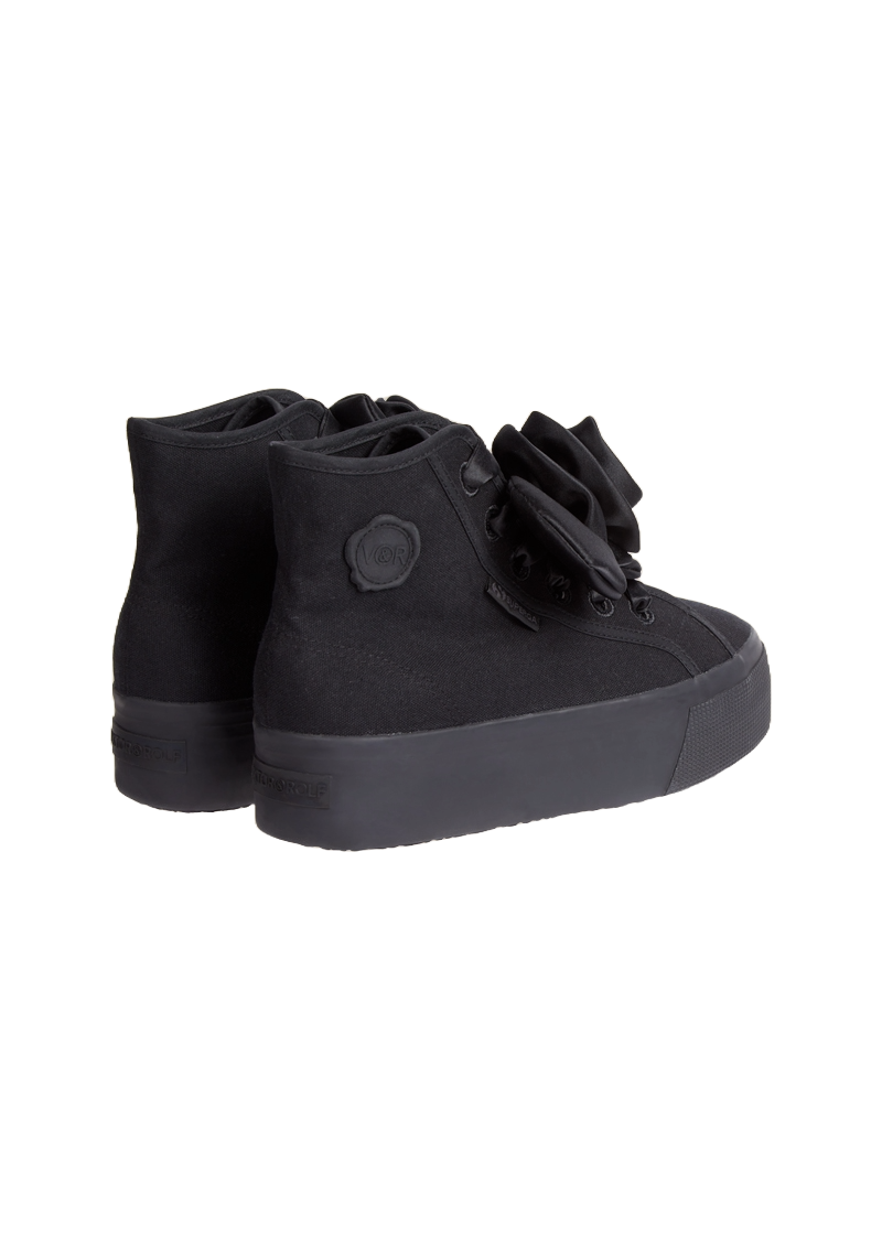 Black canvas high-top sneakers adorned with large decorative fabric flowers, featuring a subtly embossed logo on the heel.