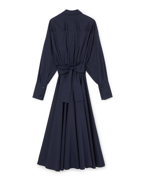 Long-sleeved navy shirtdress with a waist-tie belt and buttoned cuffs, featuring a pleated, flowing midi skirt.