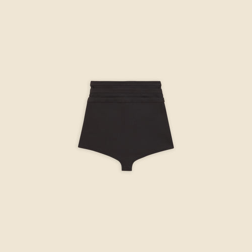 Black multi-layer shorts on a beige background.