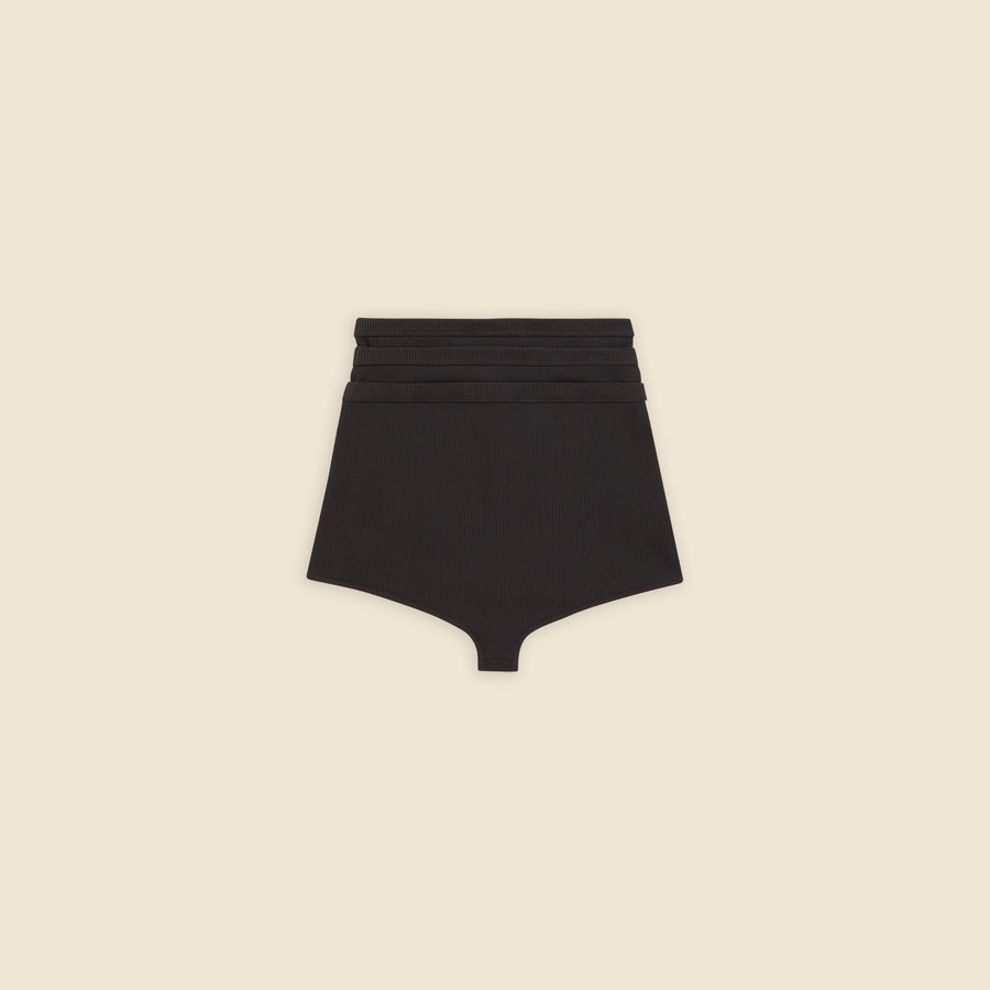 Black multi-layer shorts on a beige background.