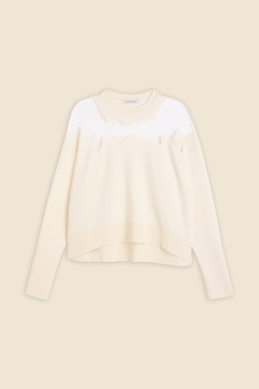 Cozy cream-colored knit sweater with a ribbed hem and cuffs, featuring modern white abstract pattern on upper chest.