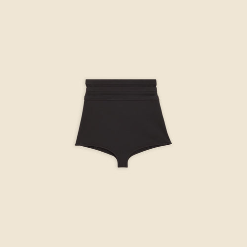 Black multi-layer shorts on a beige background.