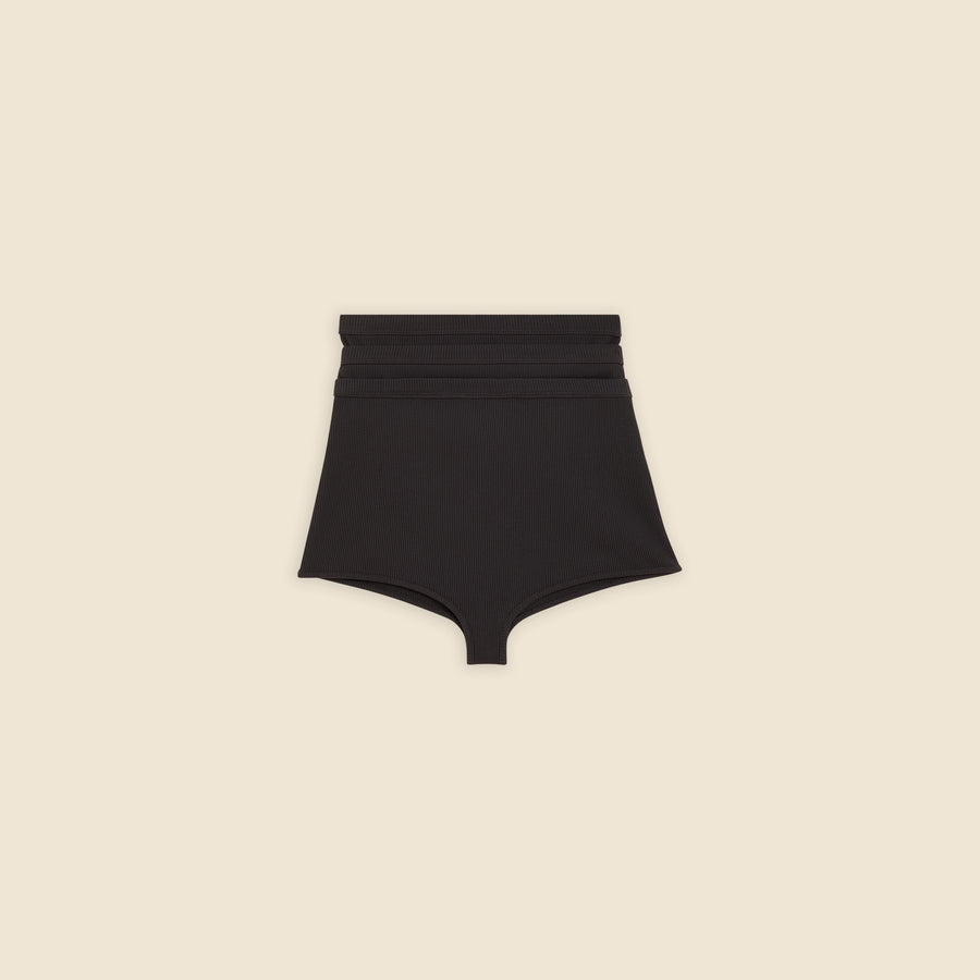 Black multi-layer shorts on a beige background.