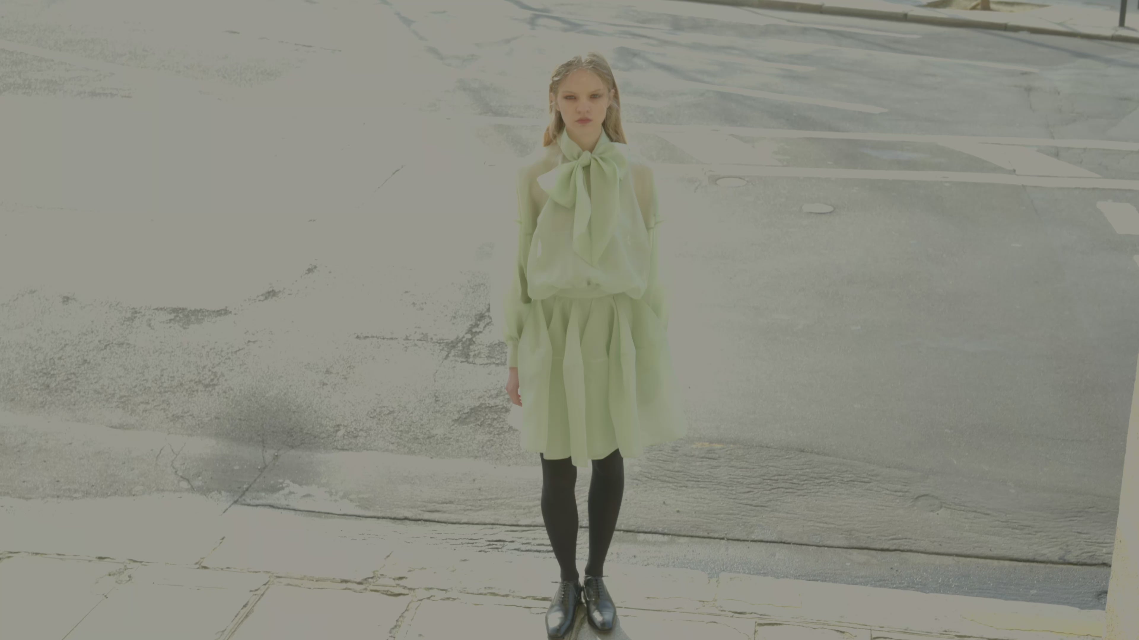 Model wearing a mint dress with a bow outdoors.