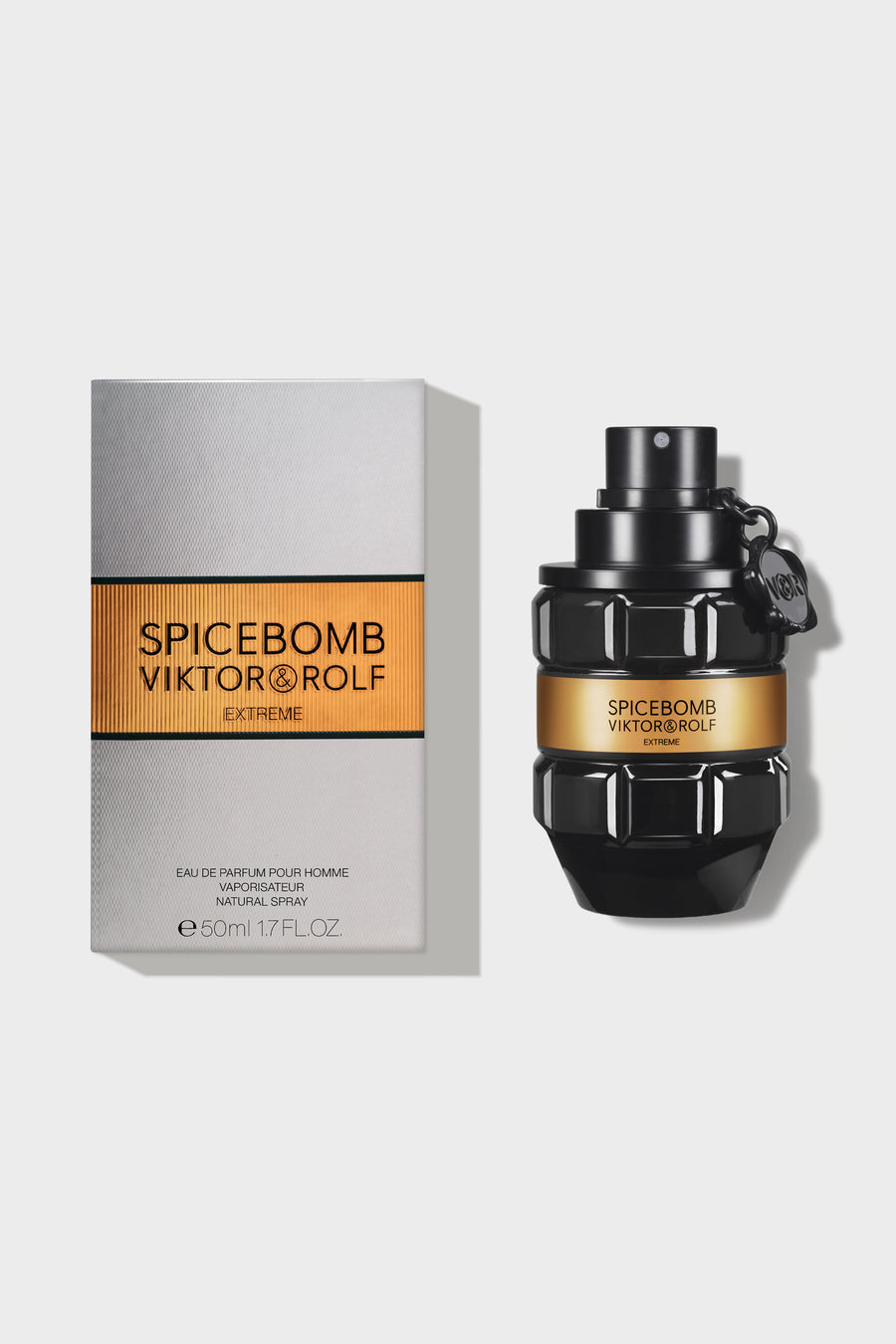 Black grenade-shaped perfume bottle with an amber label, featuring sculpted geometric facets, against a grey background.