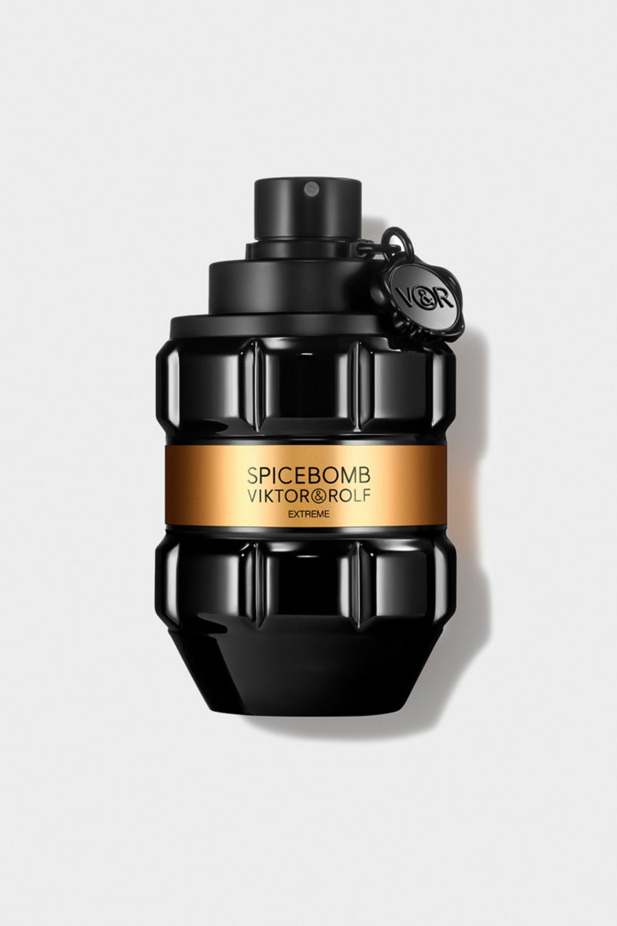 Black grenade-shaped perfume bottle with an amber label, featuring sculpted geometric facets, against a grey background.