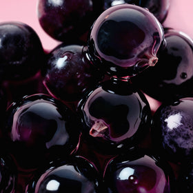 Close-up of glossy purple beads on a pink background